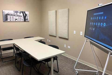 a room with tables and chairs and a smartboard computer