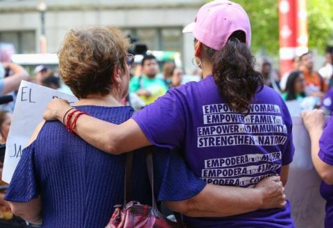 two women with their backs to the camera with their arms around each other