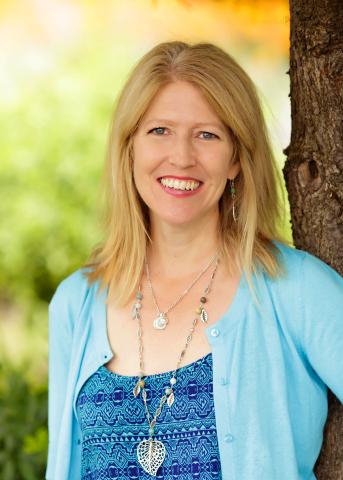 Portrait of smiling woman with long hair wearing a sweater and necklace