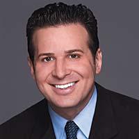 Portrait of smiling man with suit and tie and slicked back black hair