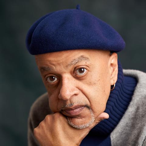 Portrait of a man with his chin in his hand, wearing a blue beret, looking serious