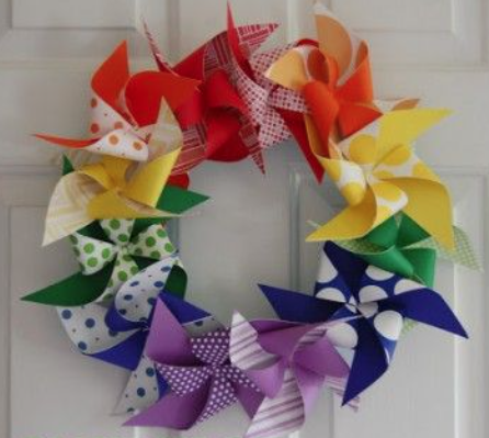 A paper wreath made out of multi-colored pinwheel shapes