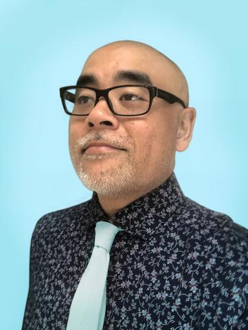 Portrait of a bald man with thick rimmed glasses, wearing a colorful tie and dark shirt