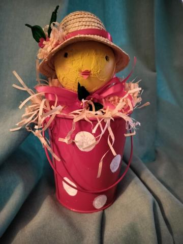 Chick wearing a hat sitting in a pink and white polka dot bucket 