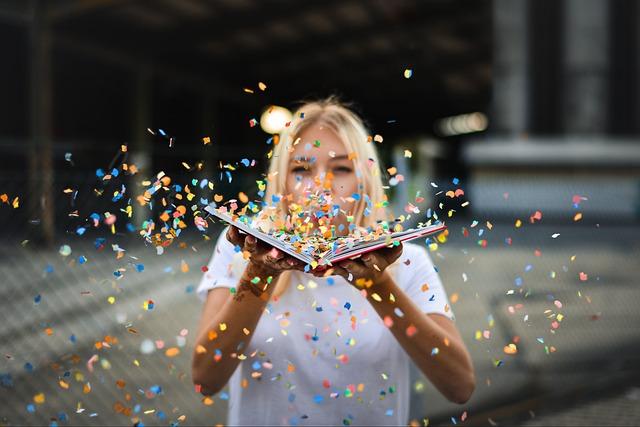 woman blowing glitter out of book