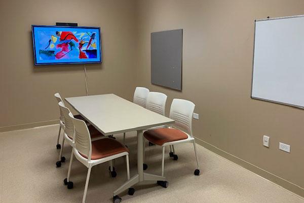 a room with a table and chairs and a big screen monitor