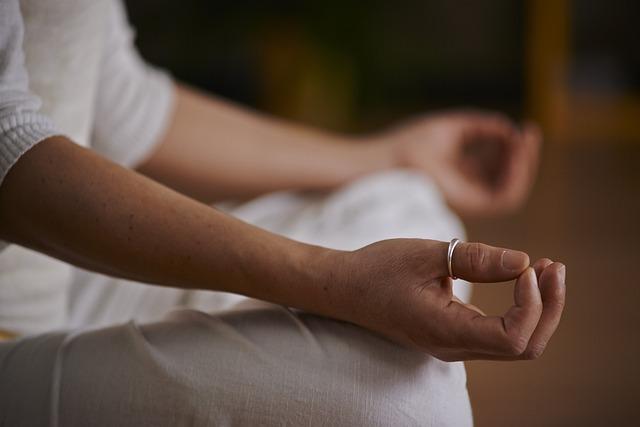 Close up photo of person cross-legged with hands upturned on knees in yoga pose