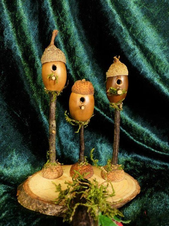 three small birdhouses perched on small branches made out of craft acorns