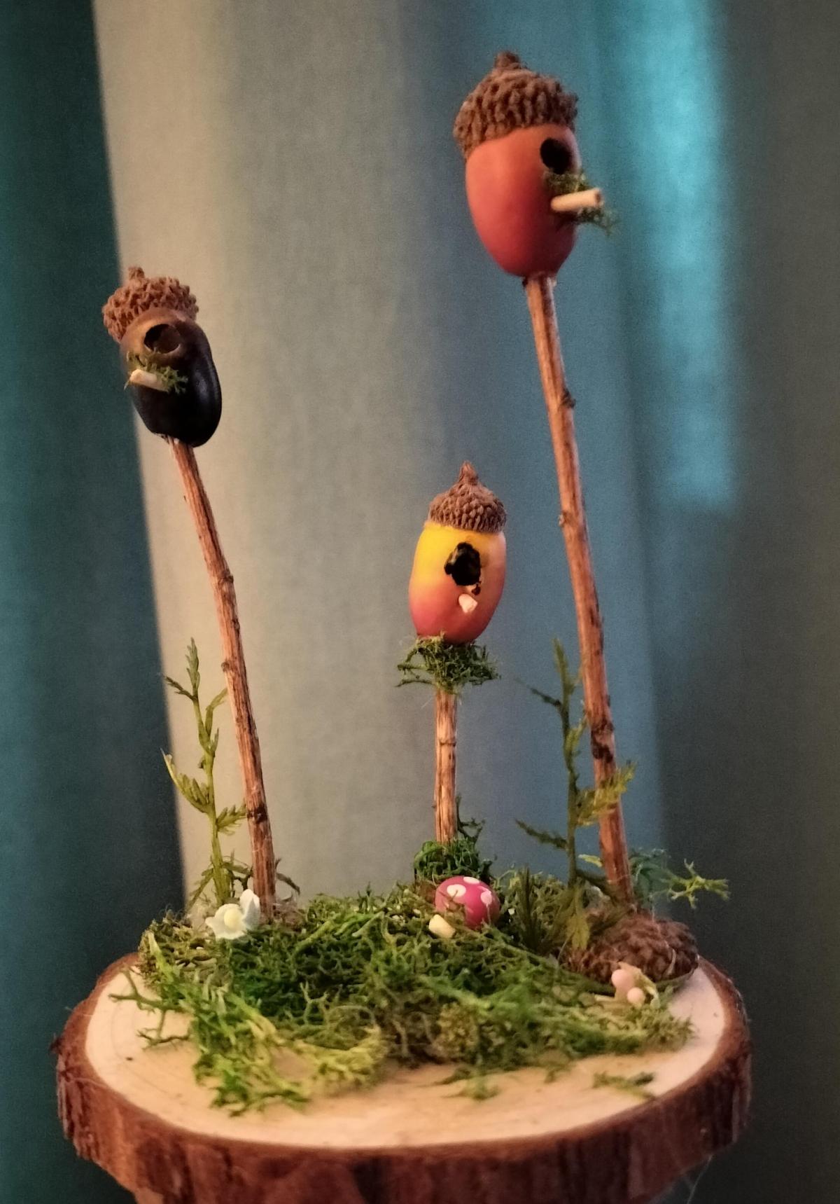 Three small birdhouses made of acorns on sticks 